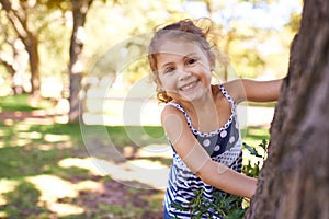 Youll never catch me. Portrait of a little girl playing hide and seek in the park.