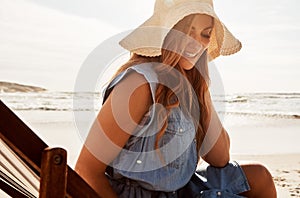 Youll often find her lounging at the beach. a young woman relaxing on a lounger at the beach.