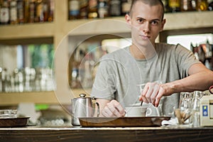 Youn waiter stirring espresso coffee for better froth