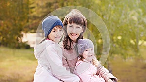 Youn woman with two daughters. Outdoors. Autumn background. Mother day