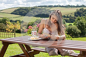 Yound attractive woman, reading a book outdoor, enjoying coffee