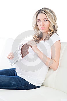 Yound pregnant blond having a bite of chocolate bar