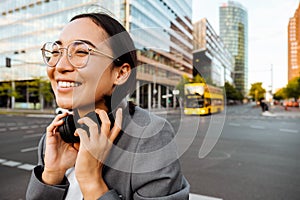 Yound woman in headphones smiling while standing outdoors