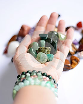 Yound woman is holding a collection of green raw mineral gemstones in her palm