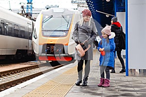 Yound woman and little girl, lovely daughter, on a railway station. Kid and woman waiting for train and happy about a