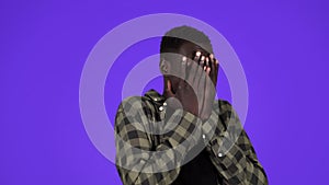 Younf African-American man feeling fear isolated on blue background. Covers his face with hands in a fear, scary of