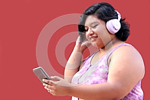 Young 20-year-old brunette and fat woman uses headphones and cell phone to listen to music, playlists, podcasts, audiobooks