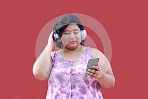 Young 20-year-old brunette and fat woman uses headphones and cell phone to listen to music, playlists, podcasts, audiobooks