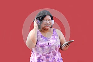 Young 20-year-old brunette and fat woman uses headphones and cell phone to listen to music, playlists, podcasts, audiobooks