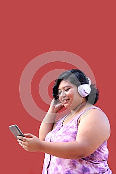 Young 20-year-old brunette and fat woman uses headphones and cell phone to listen to music, playlists, podcasts, audiobooks