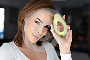 Young 30s woman holding avocado at head portrait