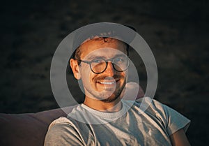 Young 32 years old Caucasian man traveler tourist with basecap on sandy beach on sand dune. Close-up summer headshot