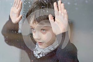 Young 7 years old boy standing beside the window