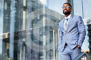 Young accomplished african american CEO business founder entrepreneur, stylish suit and glasses standing confidently at workplace