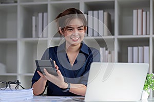 Young accountant uses a calculator to calculate taxes and manage business accounts in the office.