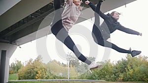 Young acrobatic girls synchronously performing split while jumping