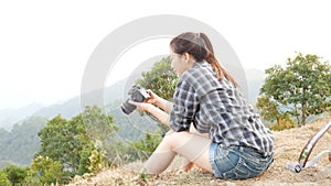 Young active Asian tourist woman travel photographer with a backpack taking pictures by digital camera at viewpoint on mountain