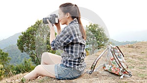 Young active Asian tourist woman travel photographer with a backpack taking pictures by digital camera at viewpoint on mountain