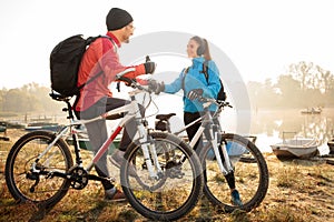 Young active couple enjoying early morning mountain bike ride by the lake