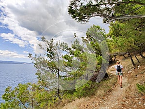 Young active feamle tourist wearing small backpack walking on co photo