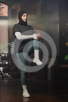 Young active female sports trainer in hijab and activewear doing exercise