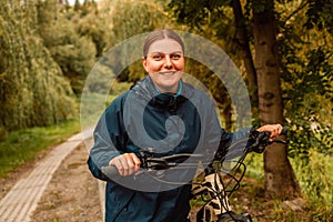 Young active girl in sportswear with a bicycle in a mountain area, enjoys summer vacation