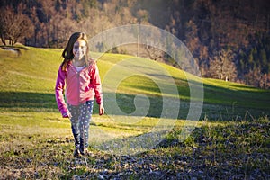 Young active girl walking over the green meadows