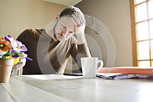 Young active man holding his head working paperwork at the desk