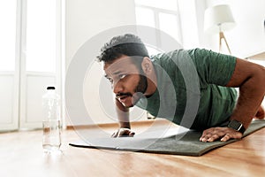 Young active man looking focused, exercising, doing push ups during morning workout at home. Sport, healthy lifestyle