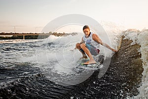 Young active man riding on the wakeboard on the lake