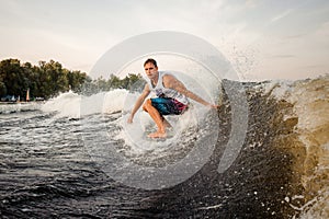 Young active man riding on the wakeboard on the open air