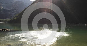 Young active man running and diving into wild sunny clear lake.Group of friends summer adventure journey in mountain