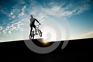 Young active sport man on bike on urban street on summer sunset blue sky