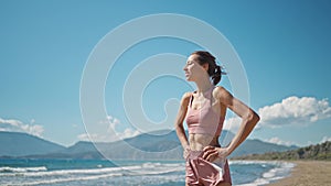 young active sporty athlete smiling woman is taking a break after making running and jogging workout on sea sandy beach