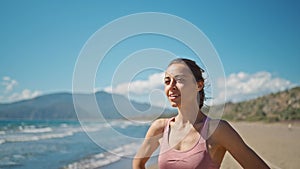 young active sporty athlete smiling woman is taking a break after making running and jogging workout on sea sandy beach