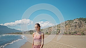 young active sporty athlete smiling woman is taking a break after making running and jogging workout on sea sandy beach