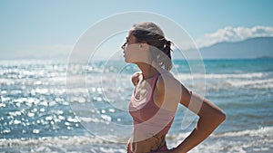 young active sporty athlete woman is taking a break after making running and jogging workout on sea sandy beach with