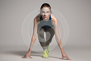 Young active sprinter woman dressed in sportswear prepare for the start.