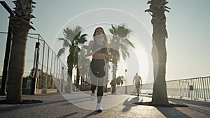 Young active woman jogging along beautiful beach. Running happy woman enjoying their summer morning workout.