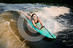 Young active woman lying on the wakesurf holding rope of motorboat photo