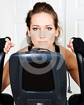 Young active woman using exercise bike for cardio workout