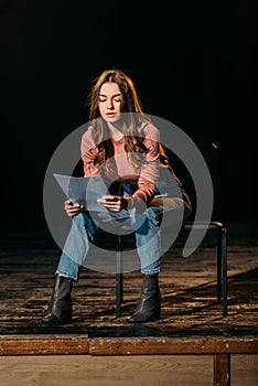 Young actress reading screenplay on stage