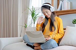 Young adorable asian woman smile wearing headset working in living room at home