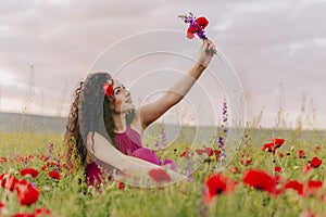 Young adorable girl wearing poppy in her hair and holding wild flowers