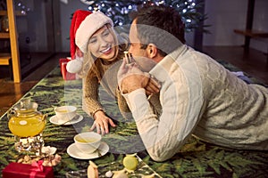 Young adorable smiling couple sitting on the floor and drinking tea for Christmas