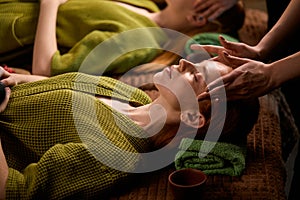 Young adorable woman in spa gets facial and head massage by professional