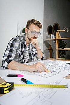 Young adult architect businessman working in modern studio with blueprints