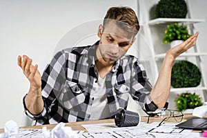 Young adult architect freelancer working with blueprints in workspace office