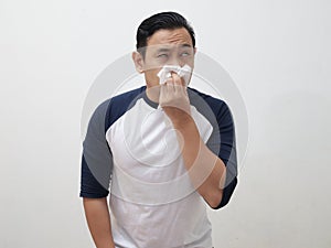 Young adult Asia man sneezing covering his nose with tissue paper,person suffer from cold or fever, health issue