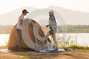 Young adult Asian couple pitch and set up tent for camping